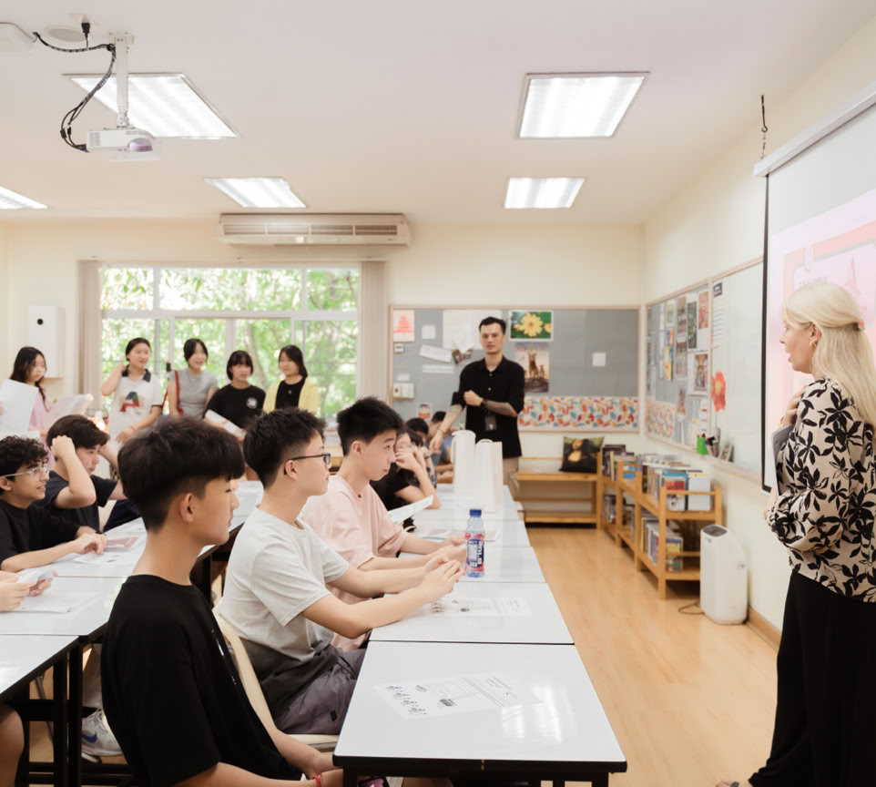 A grandmother helps her teenage granddaughter with homework, surrounded by books indoors.