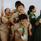 Group of diverse young scouts in uniform laughing together indoors.