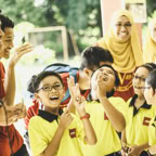 A group of school children enjoying a celebratory outdoor event with teachers in Pahang, Malaysia.